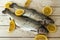 Rainbow trout over sea salt with pieces of lemon over Mediterranean wooden background