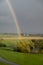 A rainbow visible very close over the green fields in southern Sweden after a summer rain