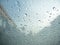 Raindrops on car\'s glass with blurry cloudy sky and village.