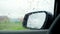 Raindrops close up. View of side mirror from inside the car with condensation and dripping rain on window. Wet glass