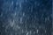 Raindrops falling against dark blue background, slow shutter speed