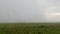 Raindrops flowing off on a window, looking out on a rural countryside landscape under a grey rainy sky