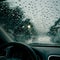 Raindrops flowing outside front windshield, close up rainy day view