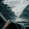 Raindrops flowing outside front windshield, close up rainy day view