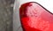 Raindrops on a red car headlight