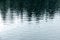 Raindrops rippling on lake with trees reflecting in water during