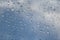 Raindrops on the window pane. Dew or condensation texture on a window against a blue sky.