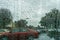 Raindrops on the windshield on a rainy day, blurred parked cars on the background, California