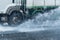 Rainwater spraying from motion truck wheels. city road during he