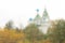 Rainy autumn day, view of the autumn forest and the church through the wet window. Autumnal sad landscape