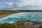 Rainy cloudscape over wavy seawater and grassy coastline