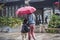 On a rainy day, a mother with a red umbrella walked past the old gate east scenic spot with a child.