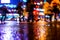 Rainy night in the big city, pedestrians cross the busy intersection in the light of shop windows.