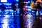 Rainy night in the big city, pedestrians cross the busy intersection in the light of shop windows.