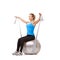 Raise those arms. A young blonde woman sitting on an exercise ball while pulling a resistance band.