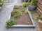 Raised bed garden with green plants and gravel path with stepping stones