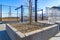 Raised concrete square beds with rocks and tree saplings at a sunny park