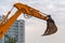 Raised excavator bucket on a background of city houses and a cloudy sky