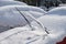 Raised windshield wipers on parked car, covered with fresh snow. Winter car maintenance in freezing weather