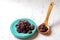 Raisins on aquamarine plate and brown wooden spoon