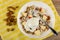 Raisins, plate with granola, yogurt, pieces of apple, spoon on napkin on table. Top view