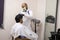 Rajasthan, india, April 24th 2020: A professional hairdresser wearing mask and gloves cutting hair to a client, Salon and
