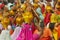 Rajasthani women wearing yellow and red sarees holding coconuts and pots take part in a religious procession in Bikaner, India.