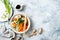 Ramen traditional japanese noodle soup with eggs, pak choi cabbage, meat broth, carrot, mushrooms in bowl on light grey background