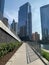 Ramp with fence shadows leading away from Chicago River, where pedestrians walk, to Wacker Drive