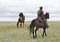 Ranch horses with riders in pasture