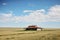 ranch house sitting on vast expanse of prairie, blue sky in the background