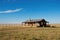 ranch house sitting on vast expanse of prairie, blue sky in the background