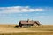 ranch house sitting on vast expanse of prairie, blue sky in the background