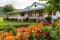 ranch house with wrap-around porch surrounded by colorful flowers