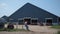 Ranch worker sitting outside big cowshed on fence after feeding livestock herd.