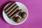 Random Chocolates in a white saucer on a pink background. Portion of assorted Confectionery. Sweet treats. Selective focus