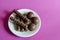 Random Chocolates in a white saucer on a pink background. Portion of assorted Confectionery. Sweet treats. Selective focus