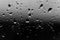 Randomly located drops of water on surface of glass, on window after rain. Black and white photo, abstract background