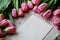 Randomly scattered pink tulips lay on a wooden texture, Kraft envelope