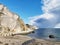 Ranvika Cove in Norway with rocky cliffs, sandy beach, and big clouds in bright sky