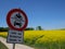 Rape field near by Gilching, upper Bavaria - yellow colza, blue sky and forest and a road sign
