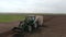 Rapeseed sowing tractor seeder selection field spring. In the background, wheat plots.