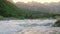 Rapid mountain river water at sunset with majestic rocky mountains at background