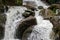 Rapid and powerful water flow between large rocks in cold mountain river, closeup