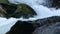 Rapid river rushing over large boulders flowing through a forest