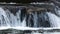 Rapid river rushing over large boulders flowing through a forest