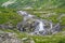 Rapid stream in mountain valley among grassy banks