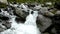 Rapids on quick mountain torrent in Alps, water is flowing over big white boulders and bubble