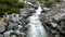 Rapids on quick mountain torrent in Alps, water is flowing over big white boulders and bubble