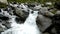 Rapids on quick mountain torrent in Alps, water is flowing over big white boulders and bubble